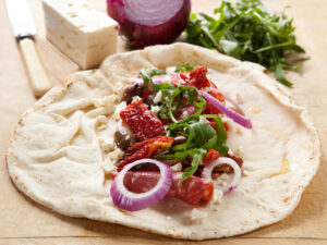 Wrap mit Feta, Rucola, getrockneten Tomaten, Zwiebeln, Salami und Oliven