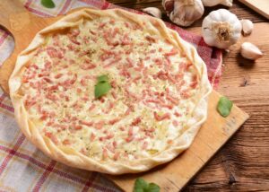 Flammkuchen mit Zwiebel- und Schinkenwürfeln und Tomatensalat