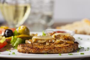 Schweinesteak mit Röstzwiebeln, Tomaten und Oliven