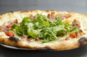 Pizza mit Parmaschinken, Rucola und Salat